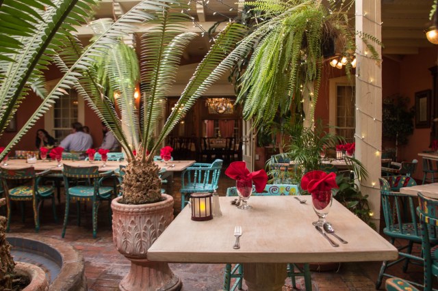 Restaurant setting with red table cloths and palms