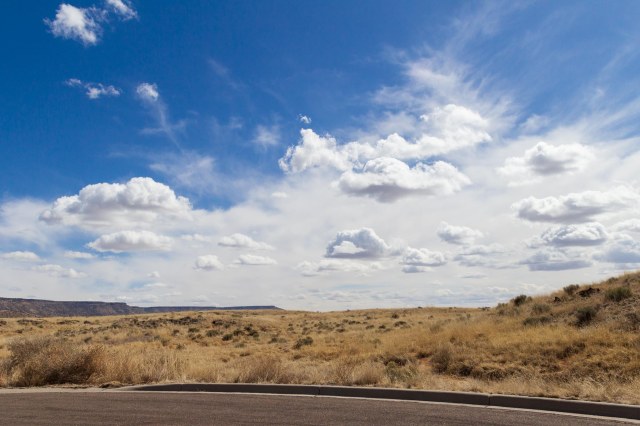 Blue skies with puffy white clouds and desert foreground