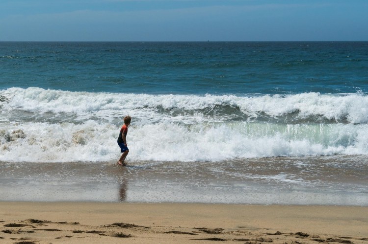 Ocean waves chasing boy on shore