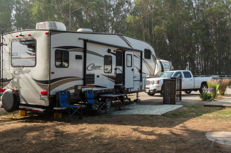 Fifth wheel trailer and white pickup campsite
