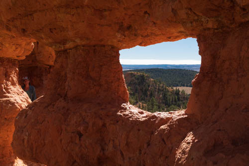 Landscape view through arch in rock formation, a person hidden in the shadows