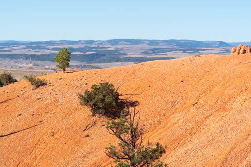 Red sandy hill with a valley in the distance