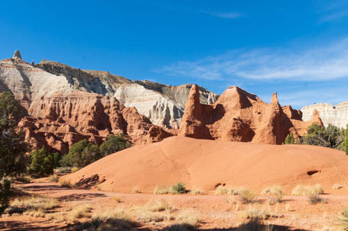 Red rock formations against back drop of tan and white formations.