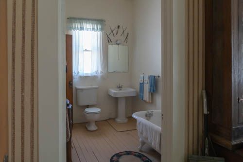 Early 1900s bathroom showing toilet, pedestal sink, and tub