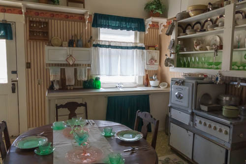 Early 1900s kitchen with stove, table, and dishware