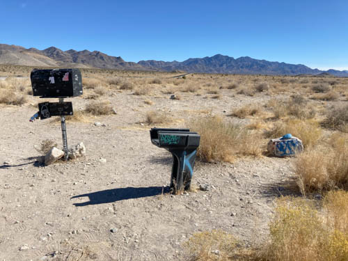 Black mailbox, broken stand for another black mailbox, and painted rock.
