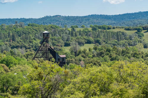 Headframe mining equipment towering over green leafed trees