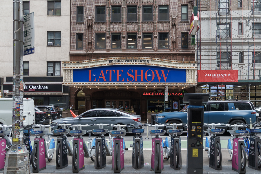 The Ed Sullivan Theater featuring 'The Late Show' marquee, with Angelo's Pizza in the foreground and bike-sharing station in the street.
